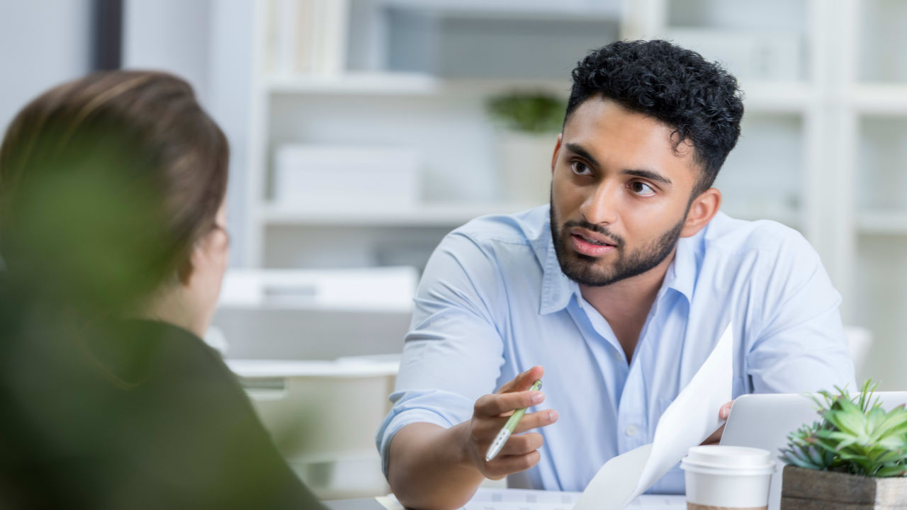 A man is talking to a woman in an office.