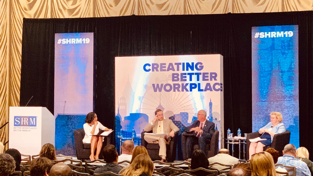 A group of people sitting on stage at a conference.