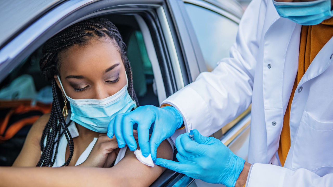 A woman is getting a vaccine in a car.