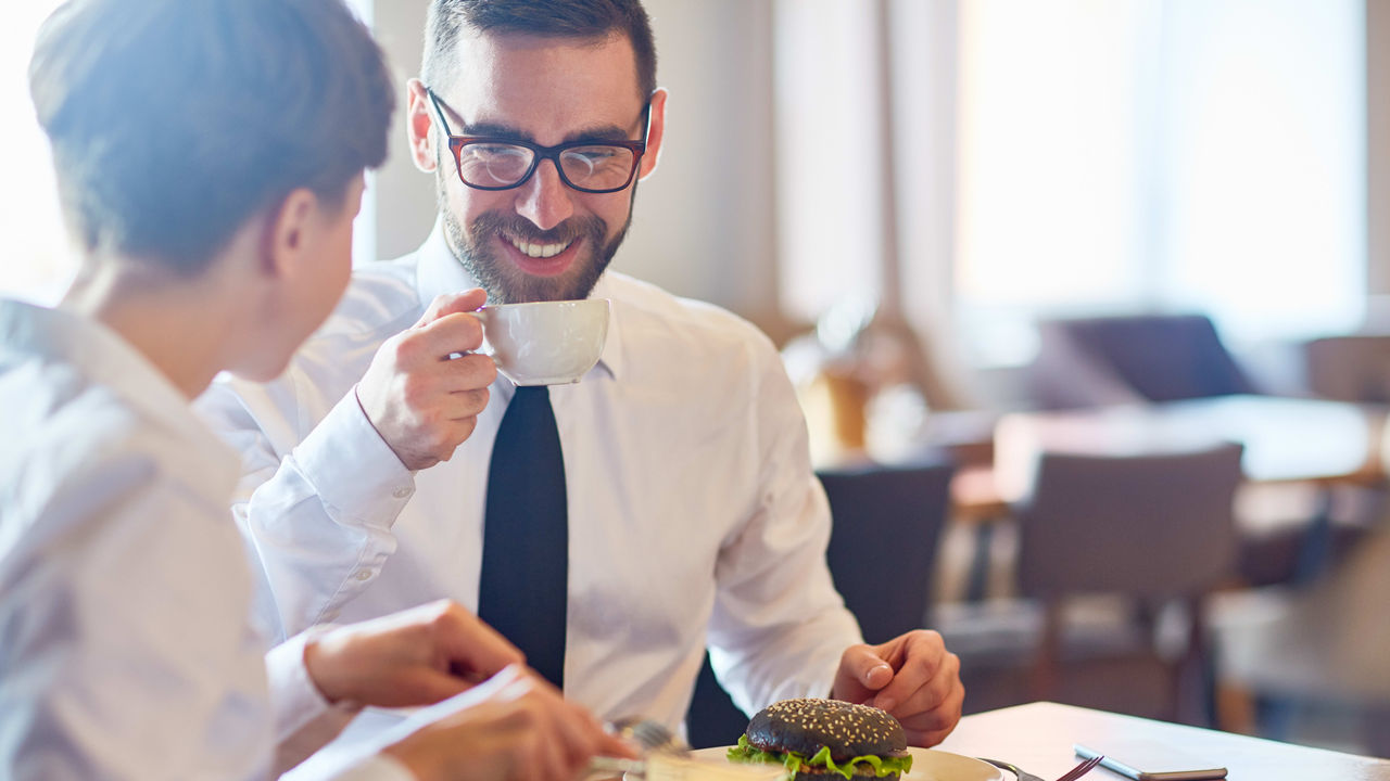 Two business people eating at a table in a restaurant.