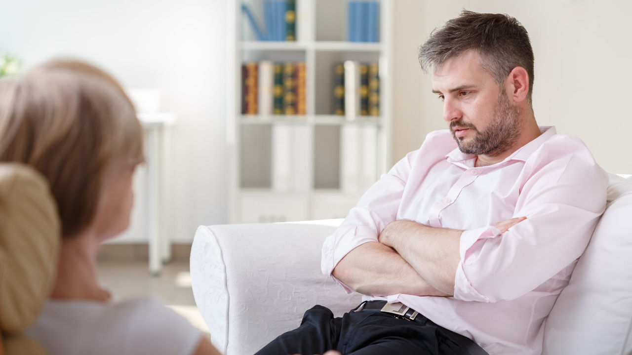 A man sitting on a couch talking to a woman.