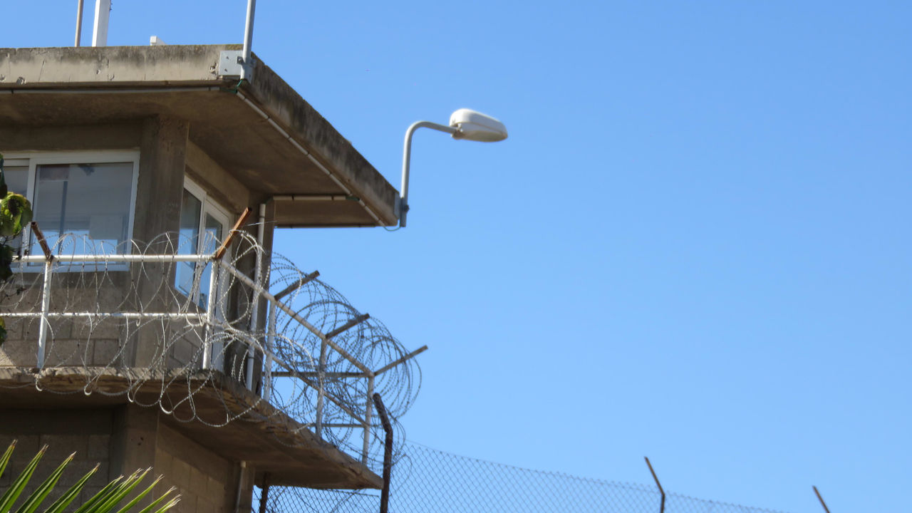 A tall building with a barbed wire fence.