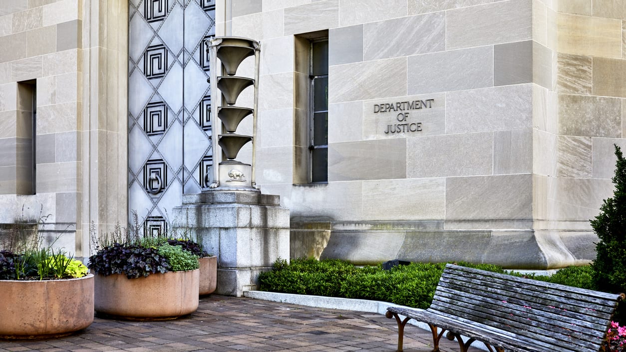 A bench in front of a building with potted plants.