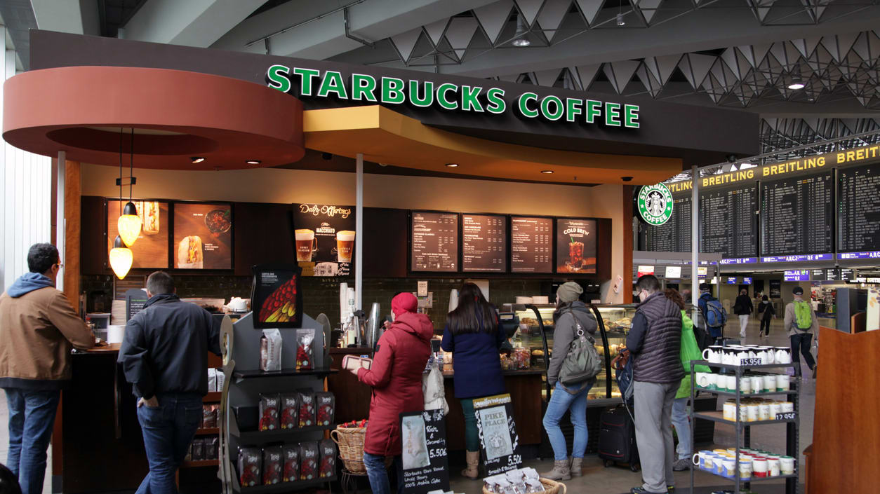 A group of people standing in front of a starbucks coffee shop.