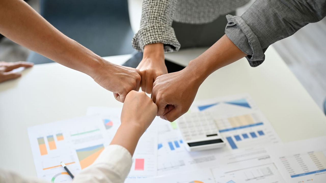 A group of business people putting their hands together on a table.