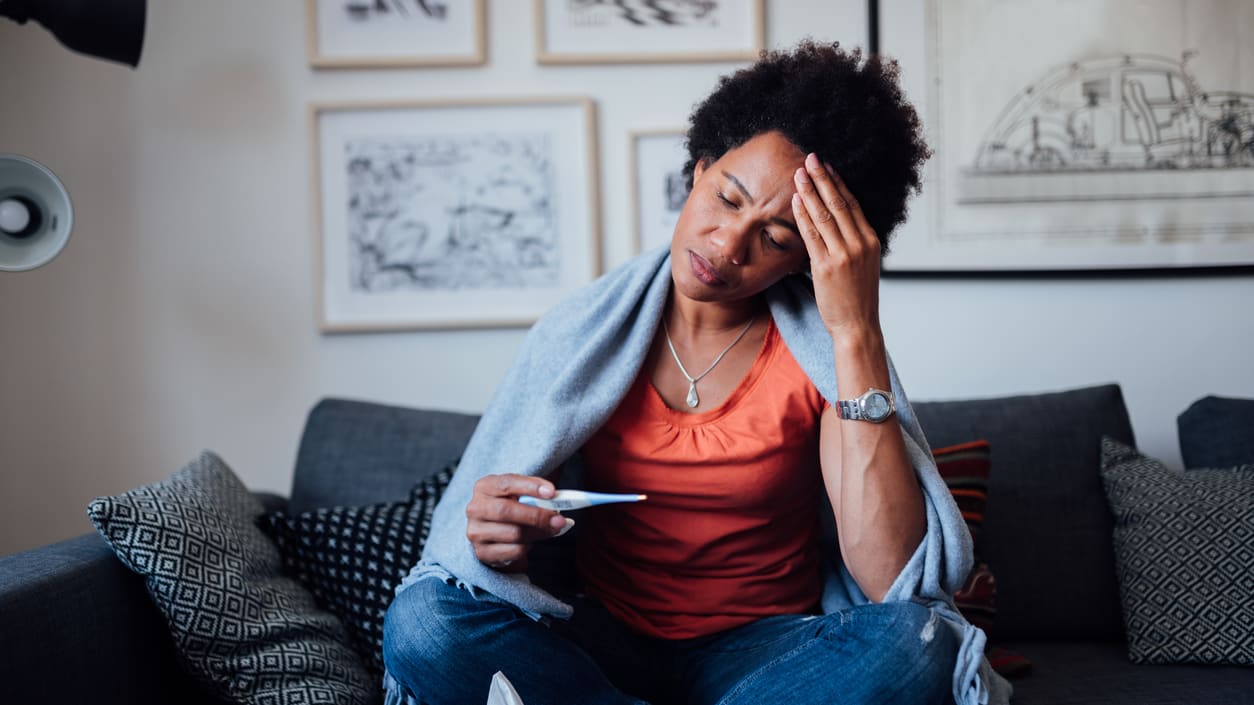 A woman sitting on a couch with her head in her hands.