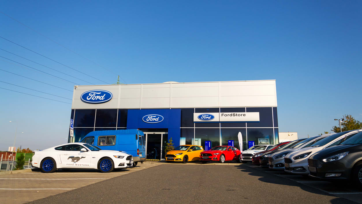 A ford dealership with cars parked in front of it.