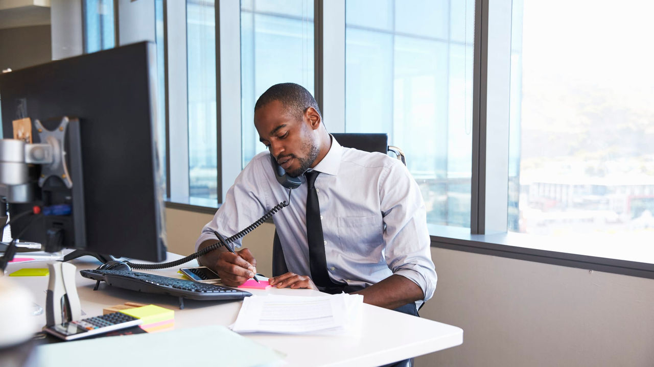 An african american businessman working at his desk in an office.