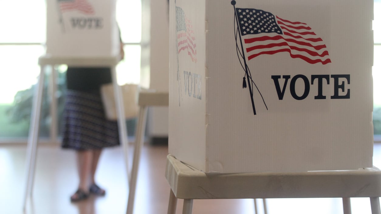 A woman is standing in front of a voting box.