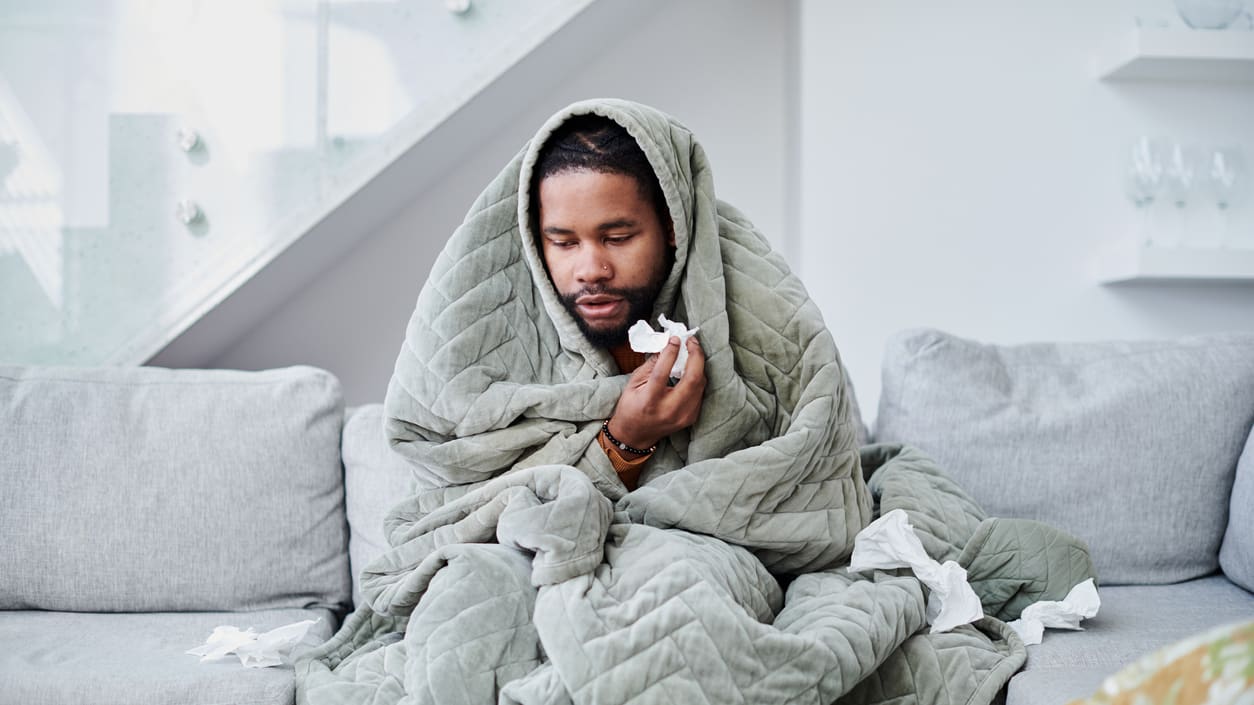 A man wrapped in a blanket sitting on a couch.