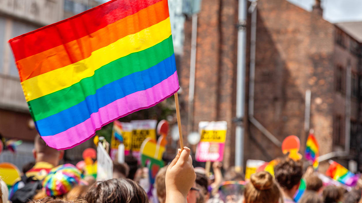 A group of people holding a rainbow flag in a city.