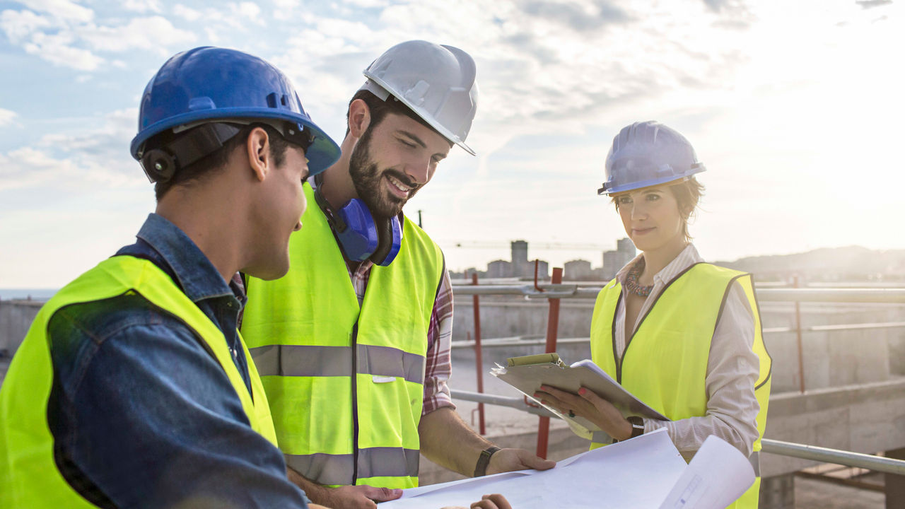 Three construction workers looking at plans on a construction site.