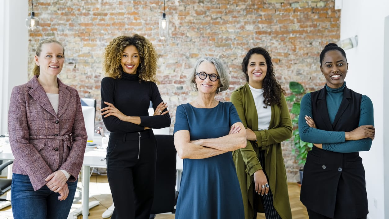 A group of business women standing together in an office.