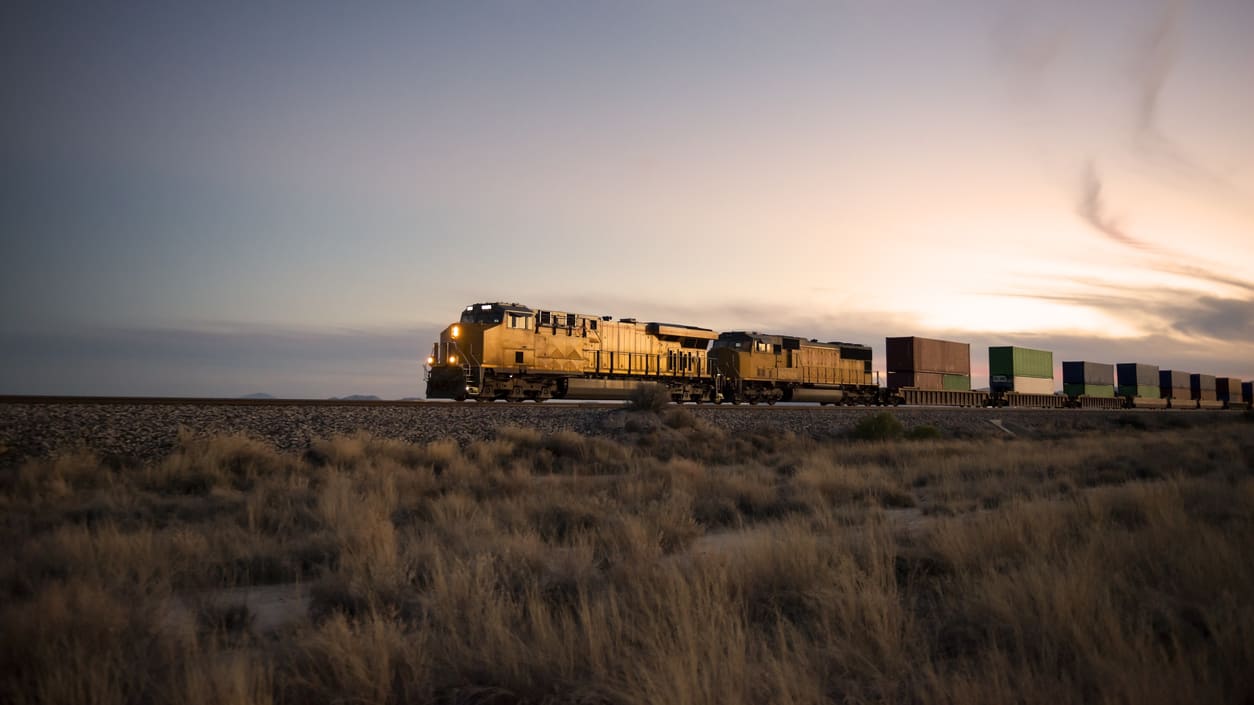 A train traveling through the desert at sunset.