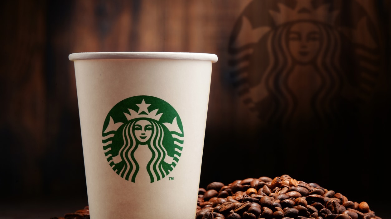 A starbucks cup sits on top of coffee beans.