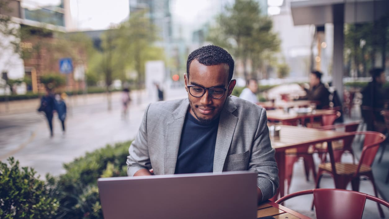 A businessman working on a laptop in an outdoor cafe.