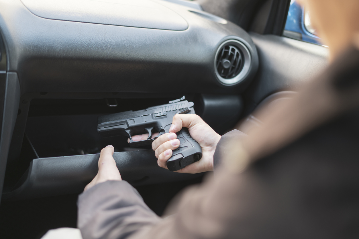 someone taking a pistol out of the glove compartment of a car