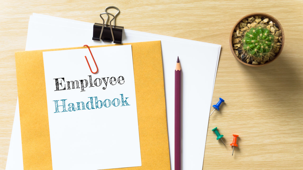 An employee handbook on a wooden table.