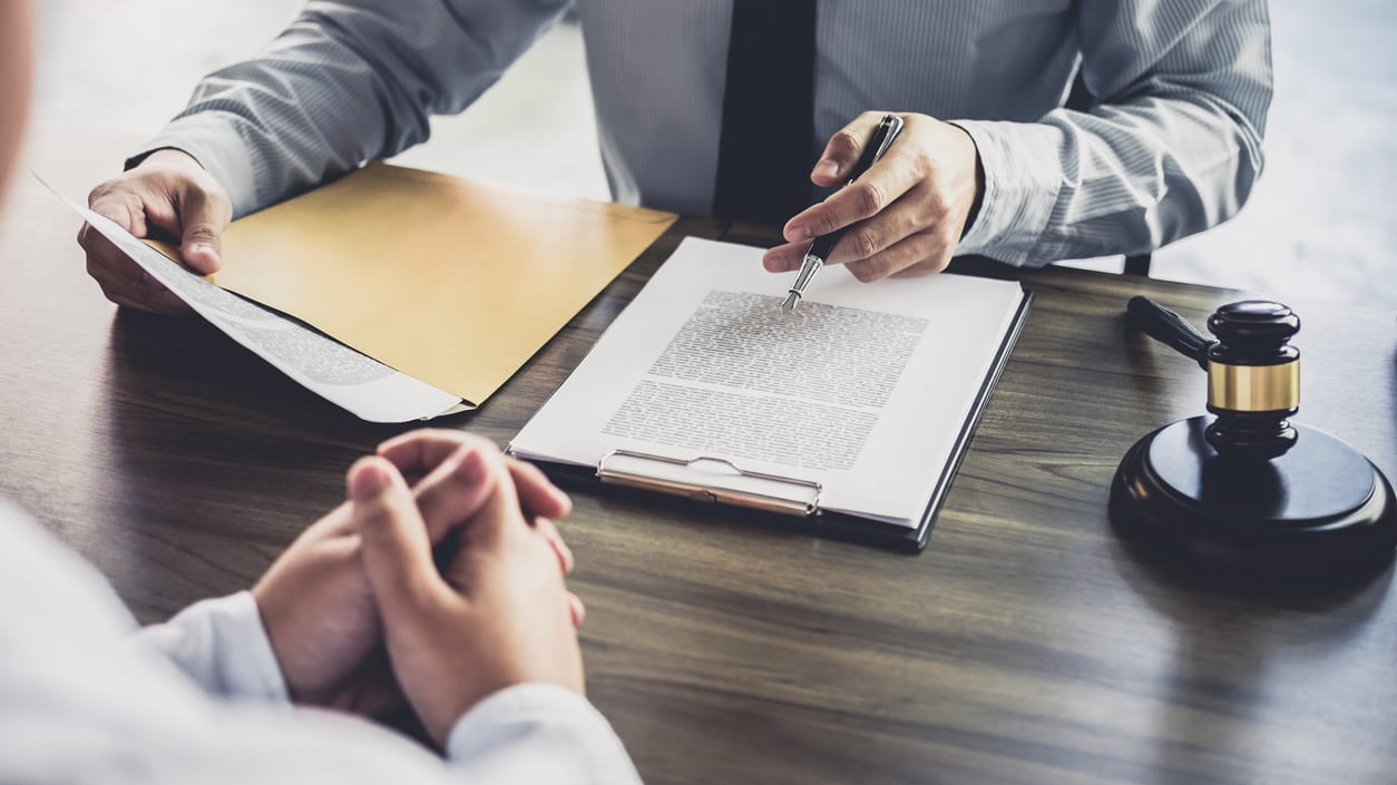 A lawyer signing a document with a gavel.