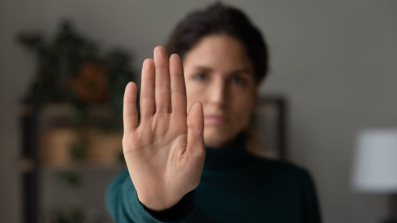 A woman is making a stop sign with her hand.