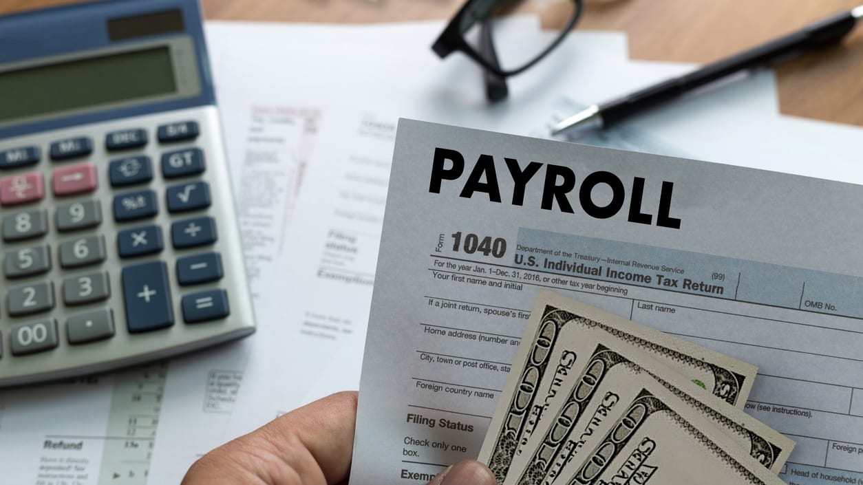 A person holding a paycheck and a calculator.
