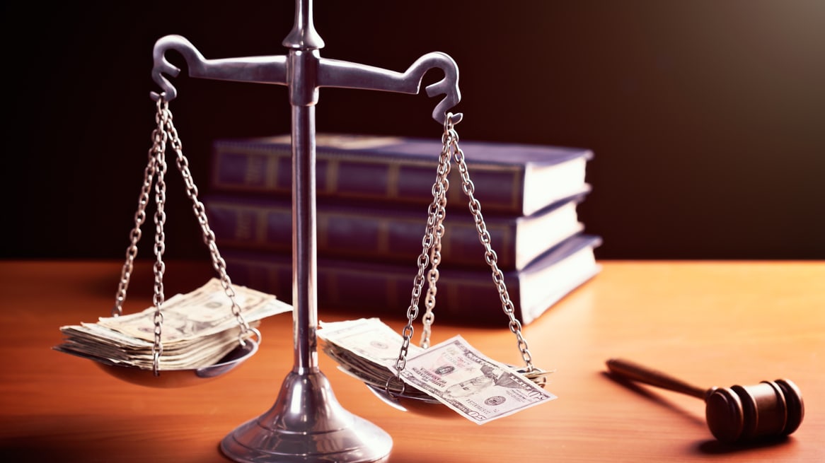 A scale with money and a gavel on it.