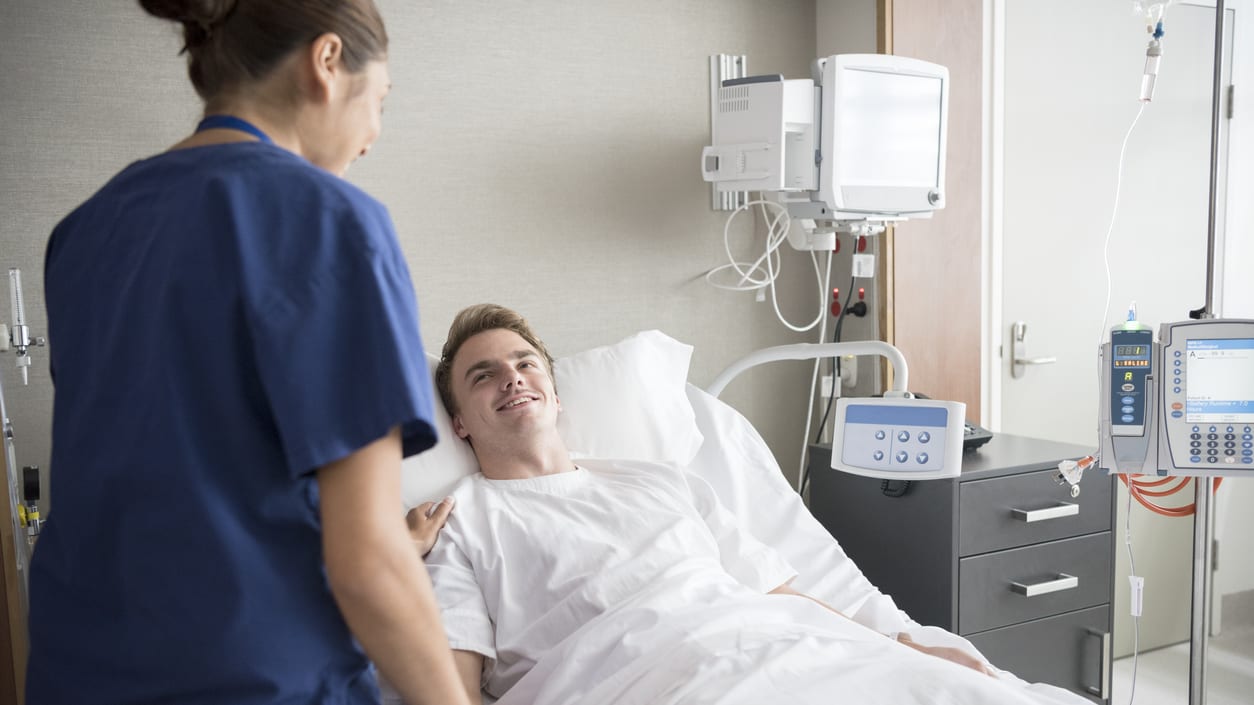 A nurse talking to a patient in a hospital bed.