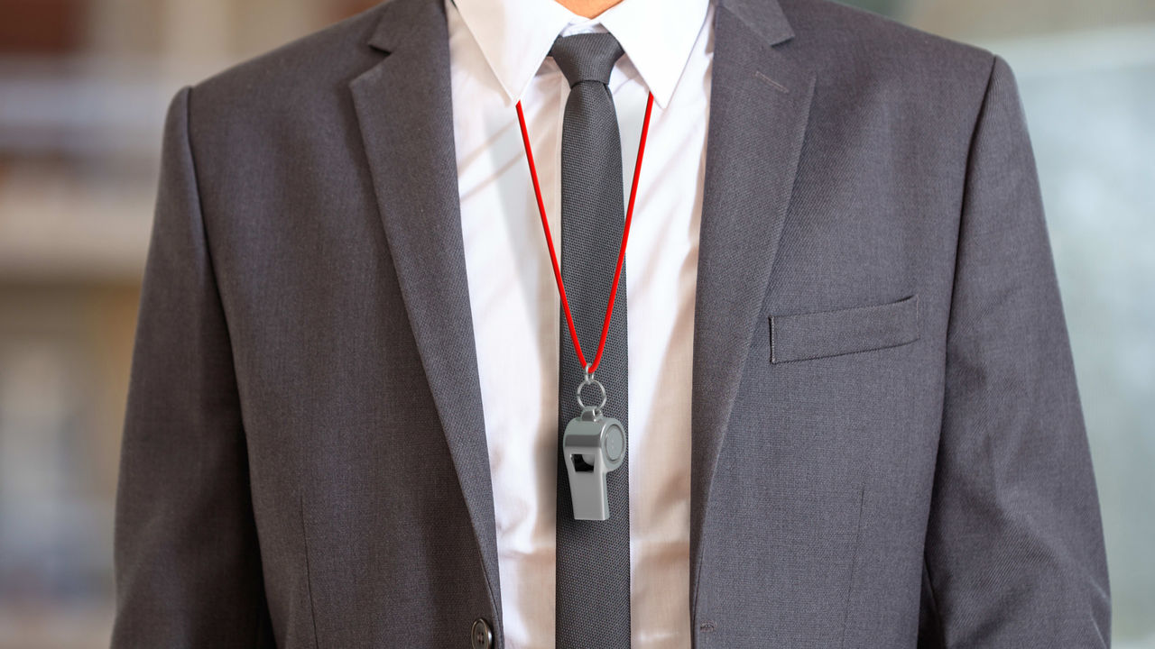 A man in a suit and tie is holding a lanyard.