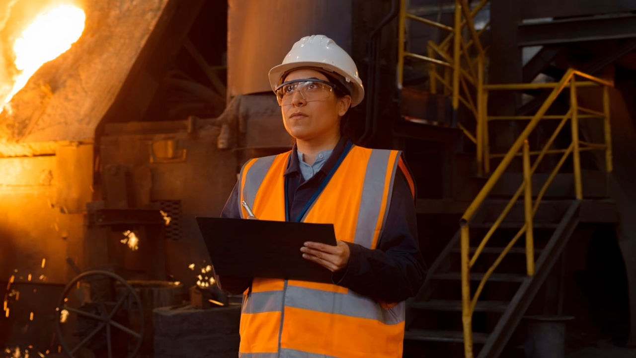 A worker at a steel factory holding a clipboard.