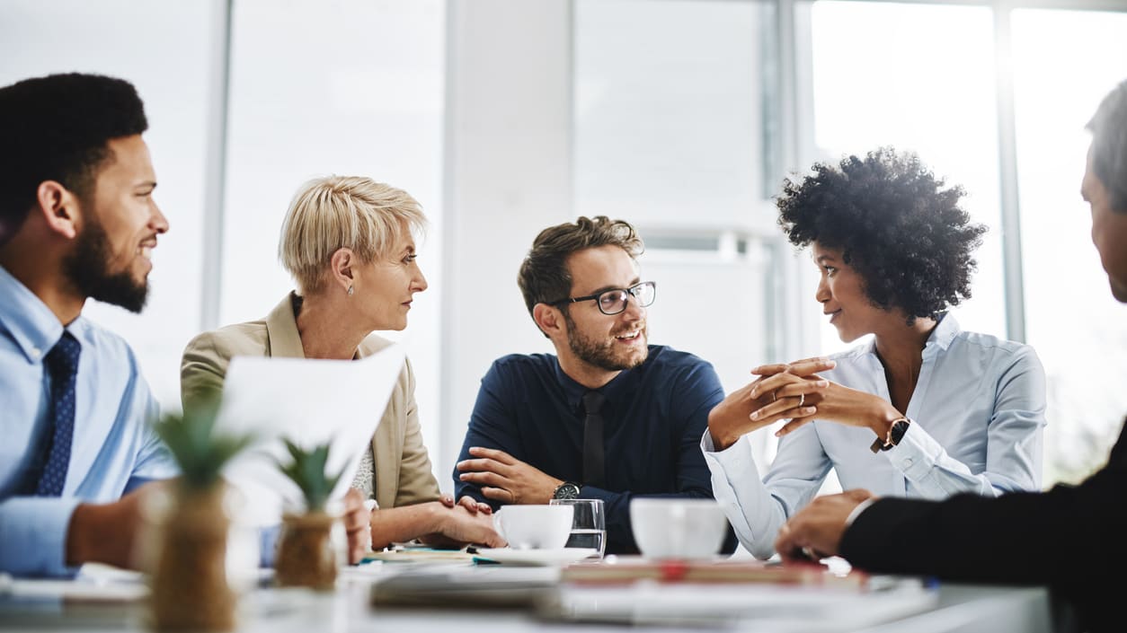 A group of business people sitting around a table in an office.