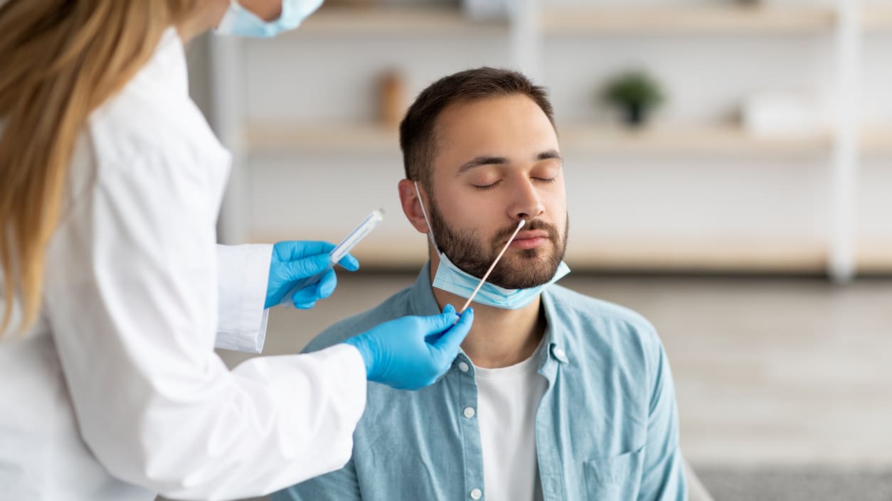 A man is being examined by a doctor wearing a mask.