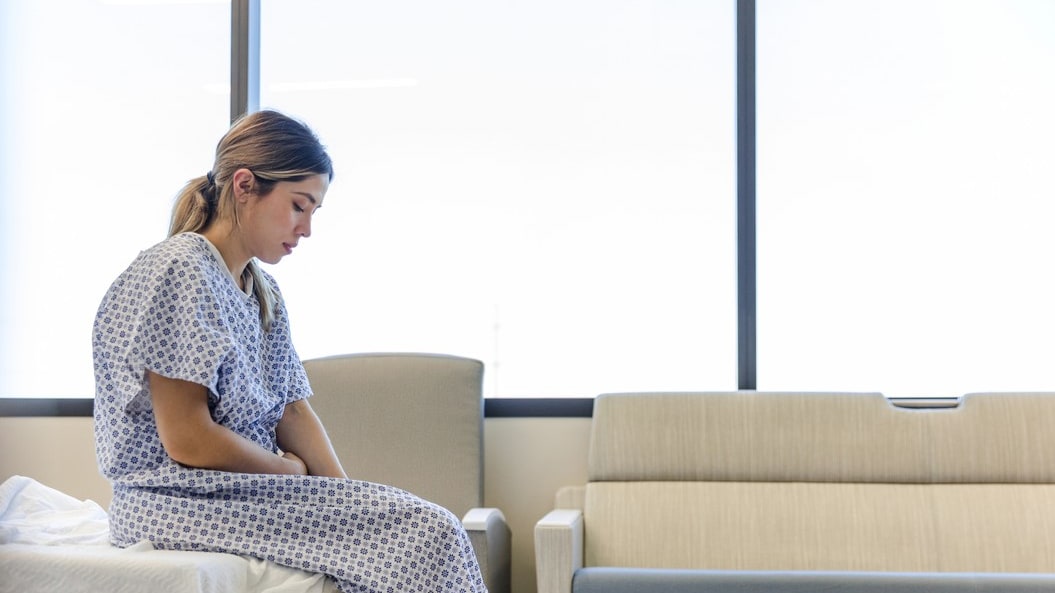 A woman sitting on a bed in a hospital room.