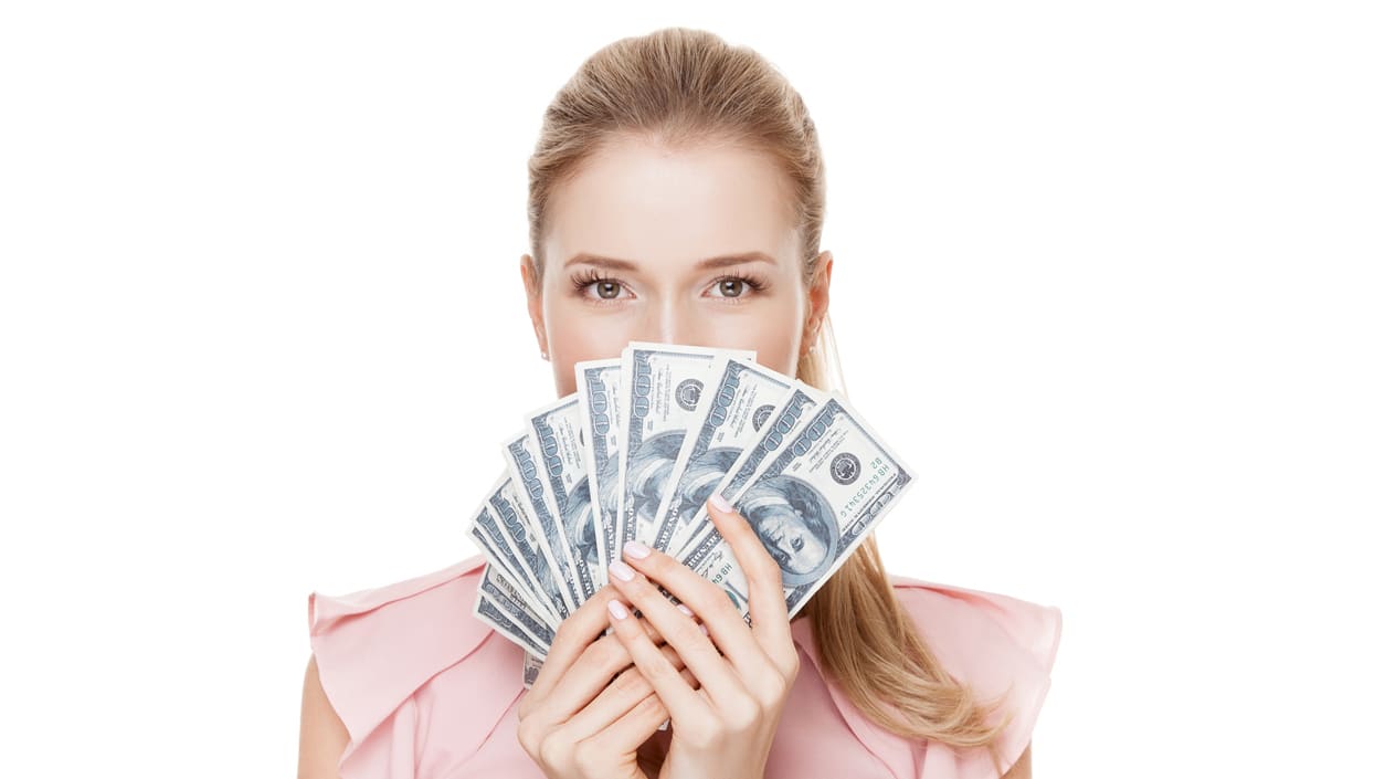A woman holding a bunch of money in front of her face.
