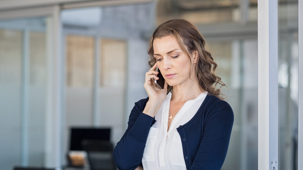 A woman is talking on the phone in an office.