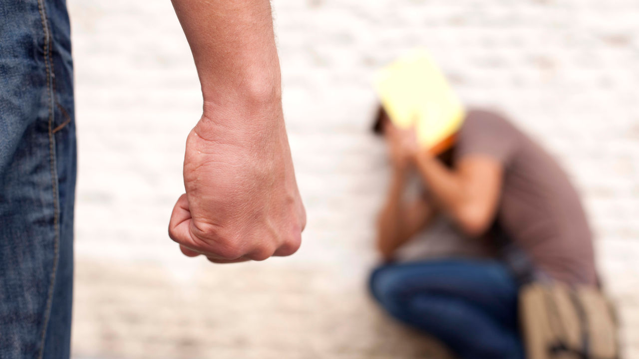 A man is holding his fist in front of a brick wall.