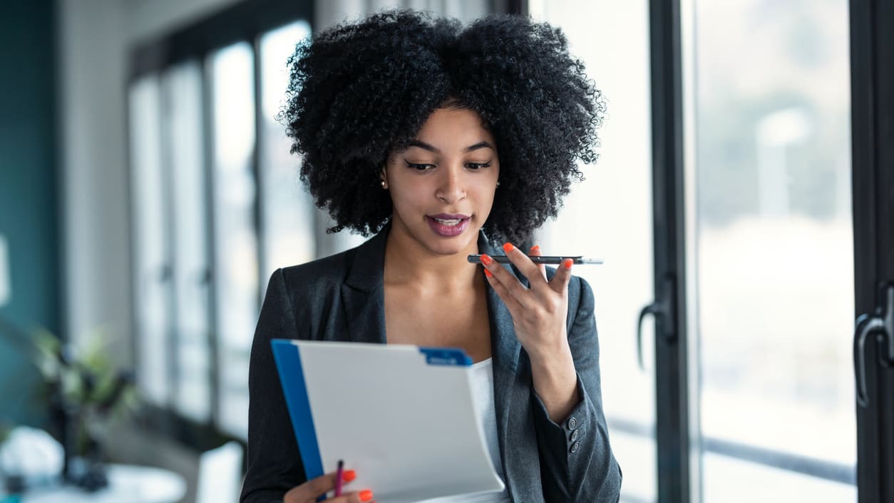 Professional worker looking over some business documents that she's carrying while standing.