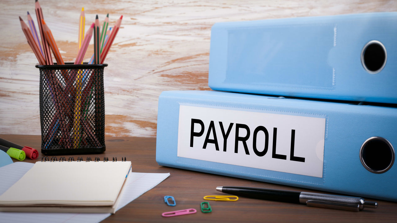 Two blue binders with the word payroll on them.