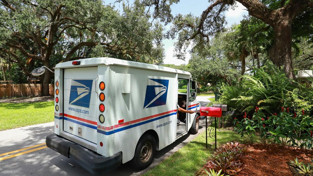 A us postal truck is parked on a street.
