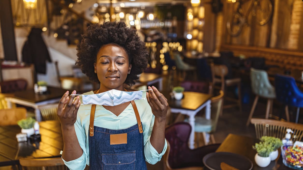 A woman in an apron holding a piece of bread in a restaurant.