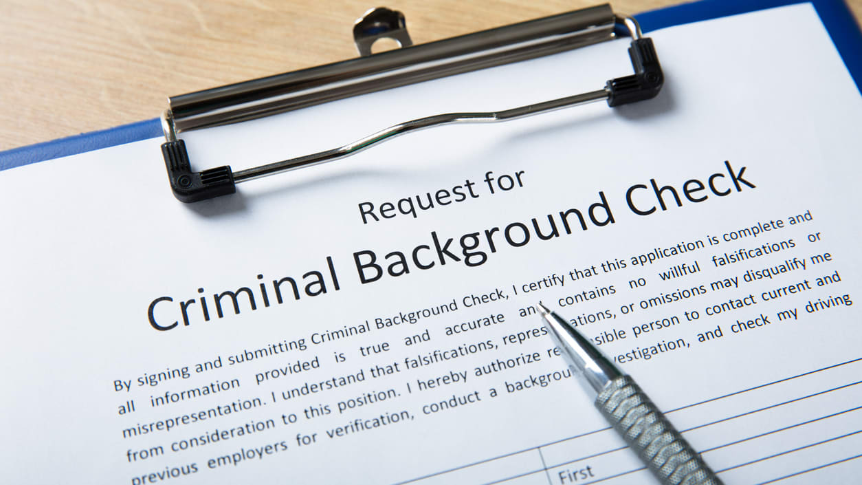 A request for criminal background check is sitting on top of a clipboard.