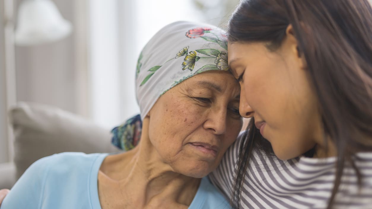 A woman is hugging an older woman on the couch.