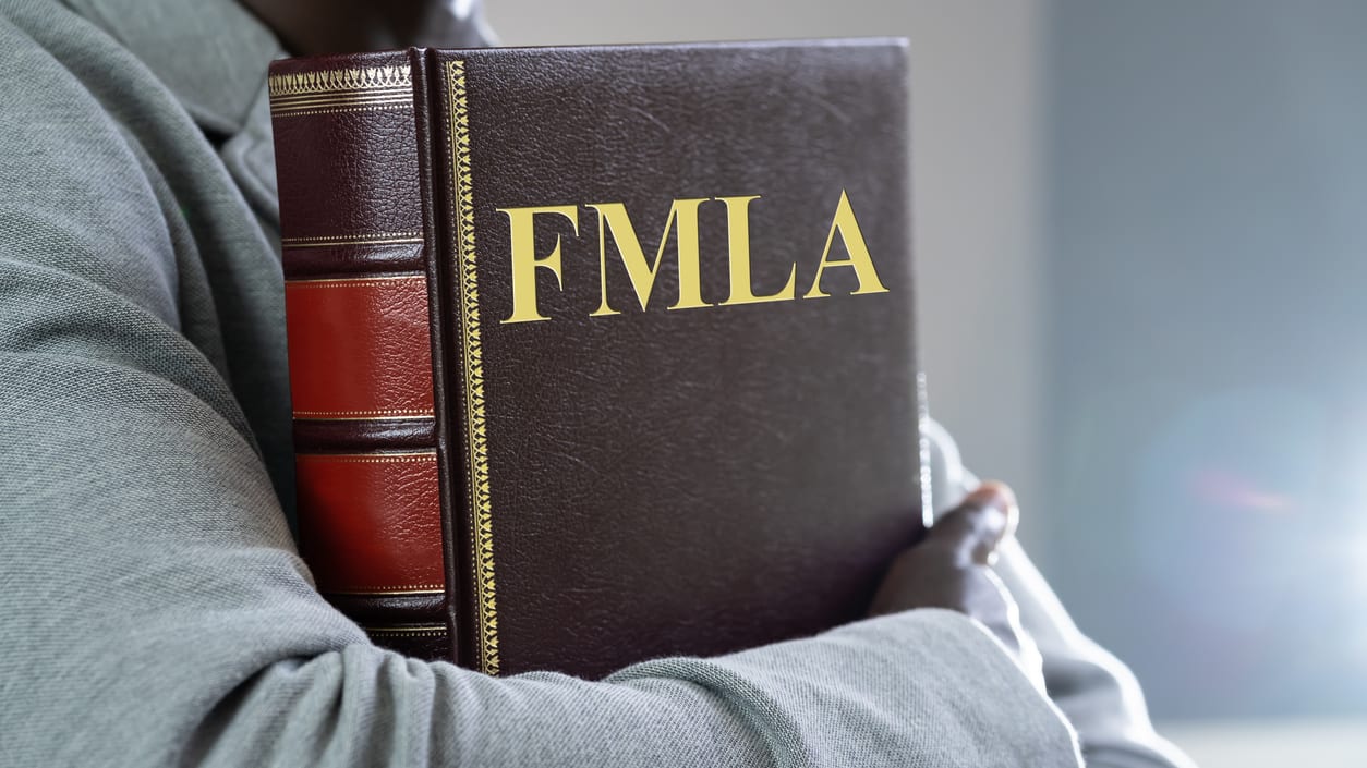 A man holding a book with the word fmla on it.