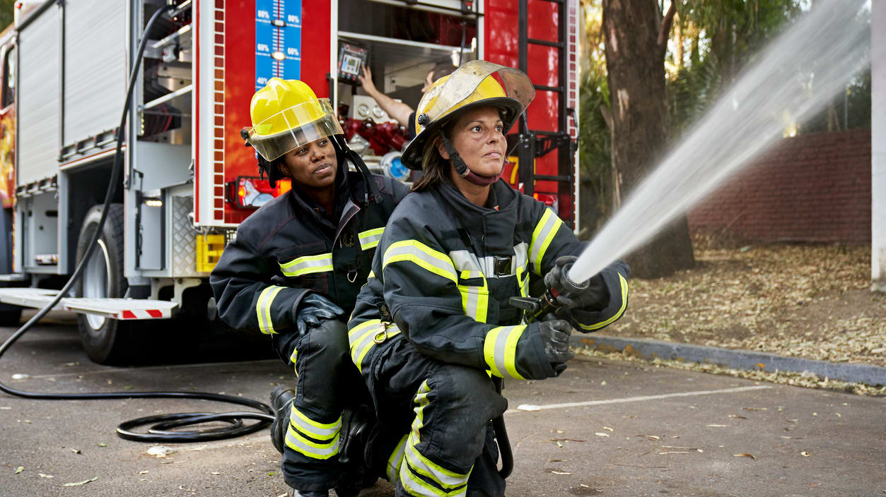 Two firefighters spraying water from a hose.
