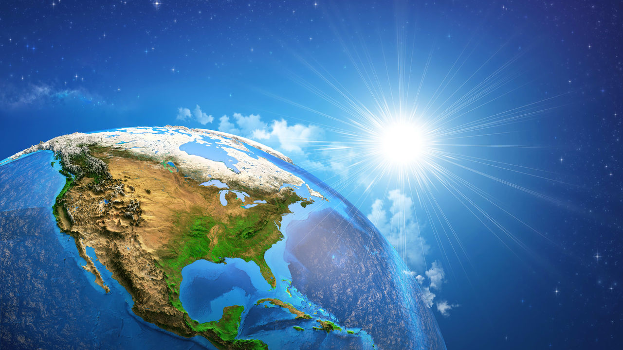 The earth in space with the sun shining on it.