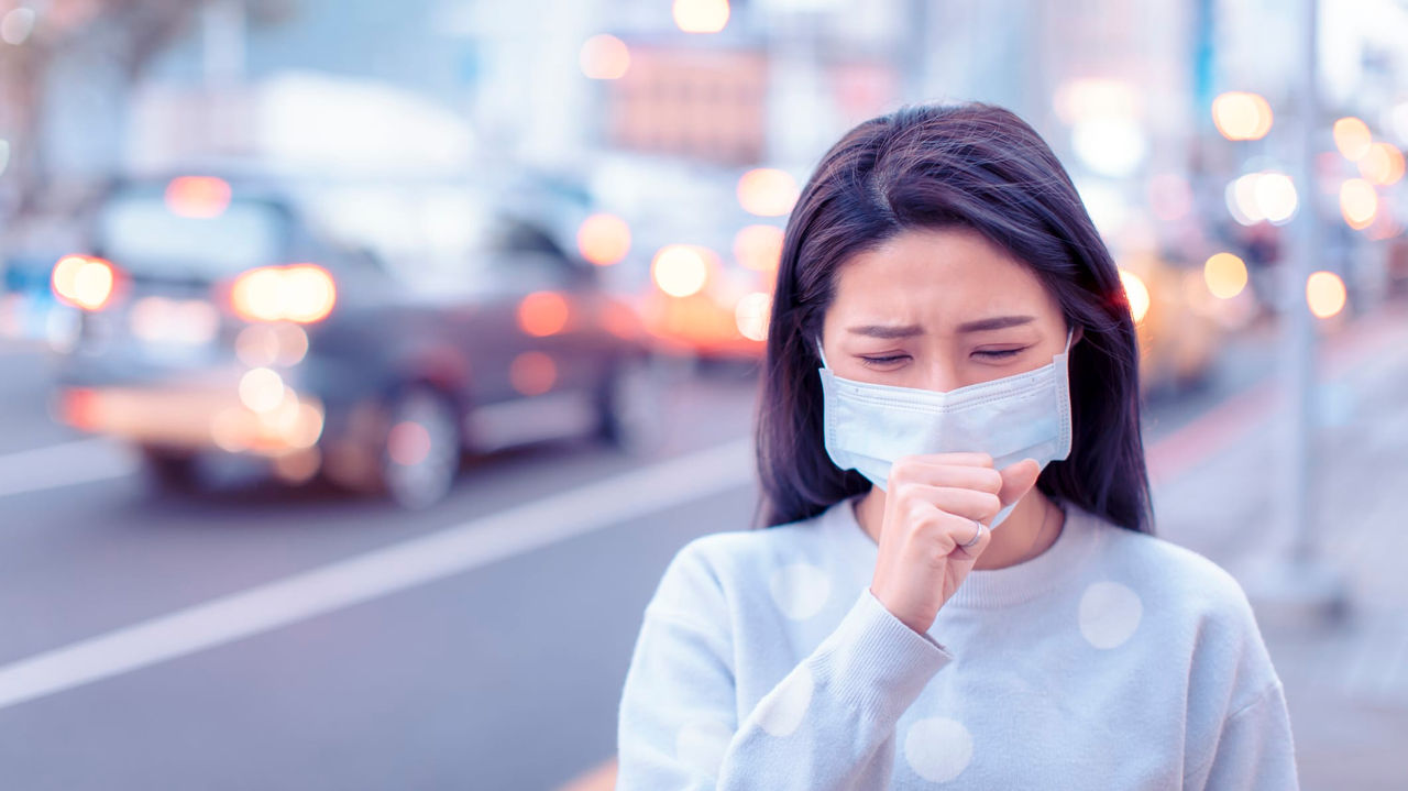 A woman wearing a face mask on a city street.