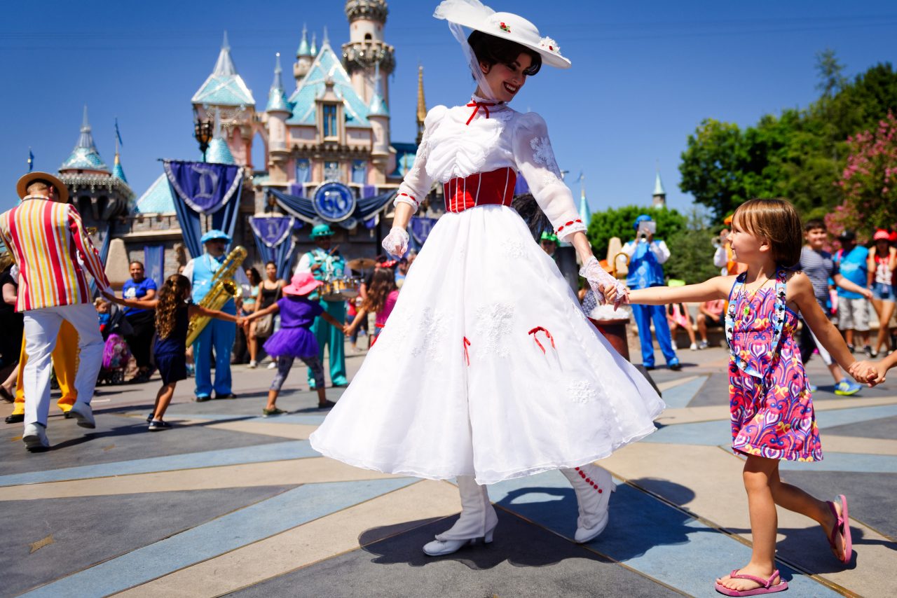 Woman dressed as Mary Poppins holds child's hand at Disneyland, California. 