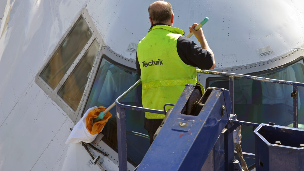 A man cleaning the wing of an airplane.