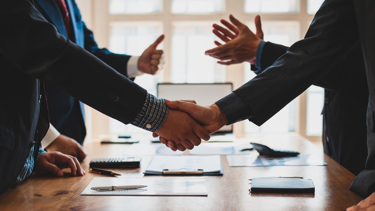 A group of business people shaking hands over a table.