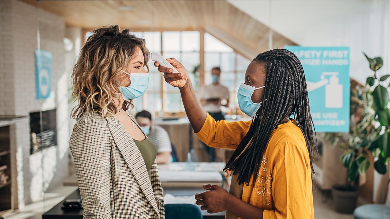 Two women wearing face masks in an office.