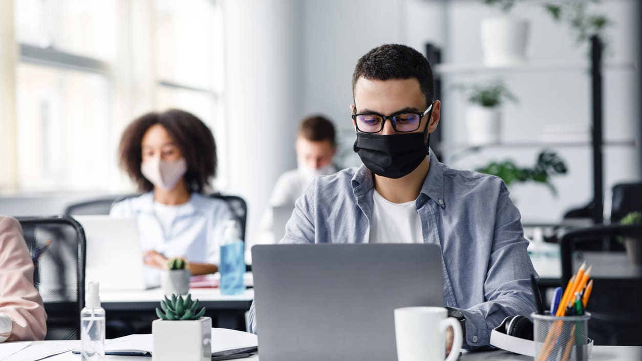 A group of people wearing face masks in an office.